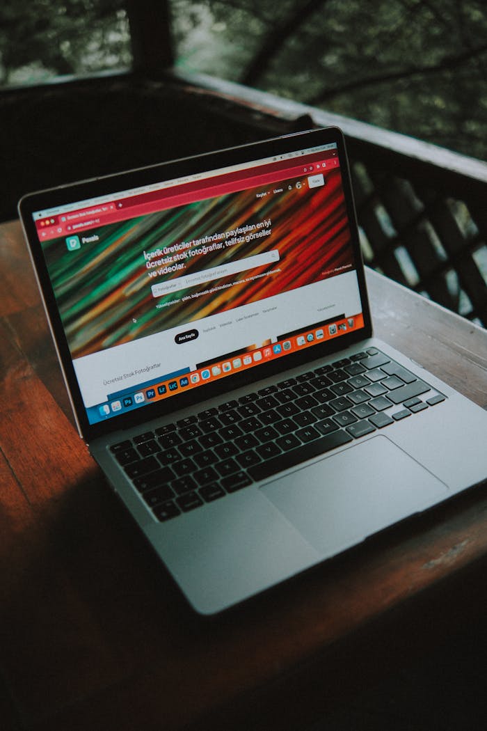 A close-up view of a laptop with a website open, placed on a wooden table near a window.