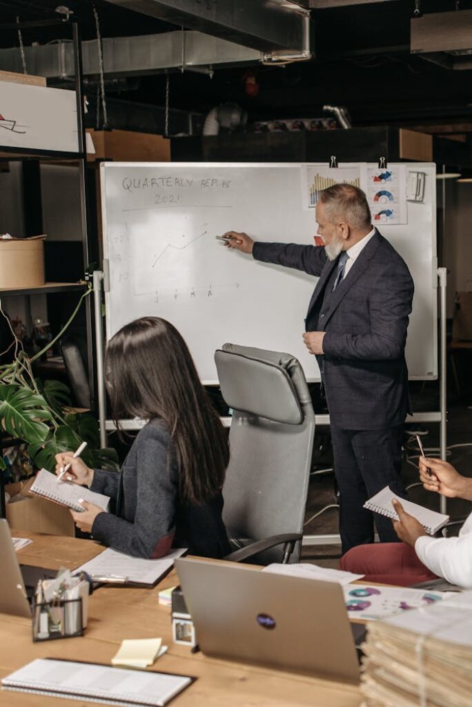 Corporate meeting scene with a presenter analyzing quarterly returns on a whiteboard in an office setting.